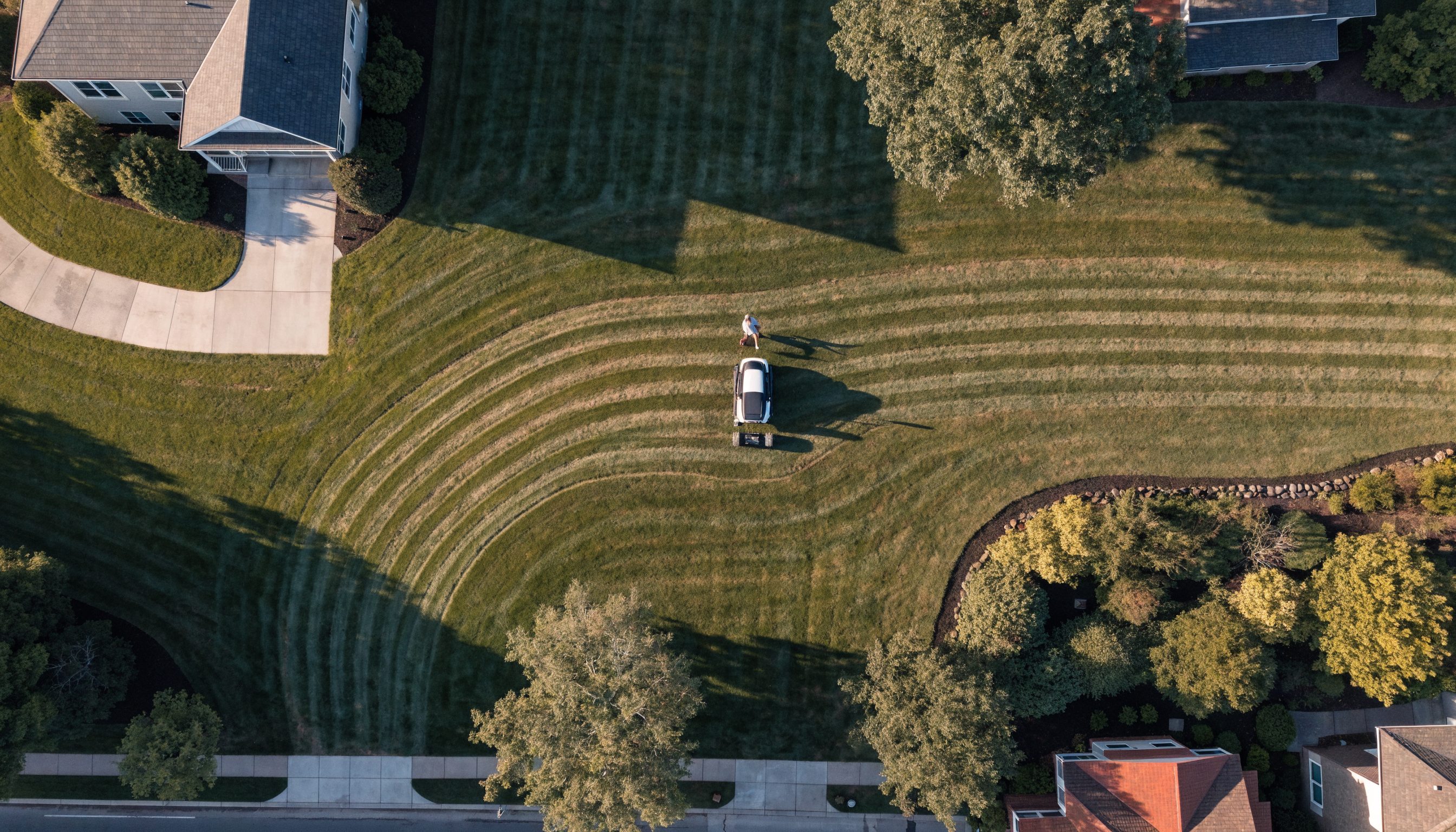 Aerial drone view of a person mowing a large green lawn with a riding mower in Clarksville TN