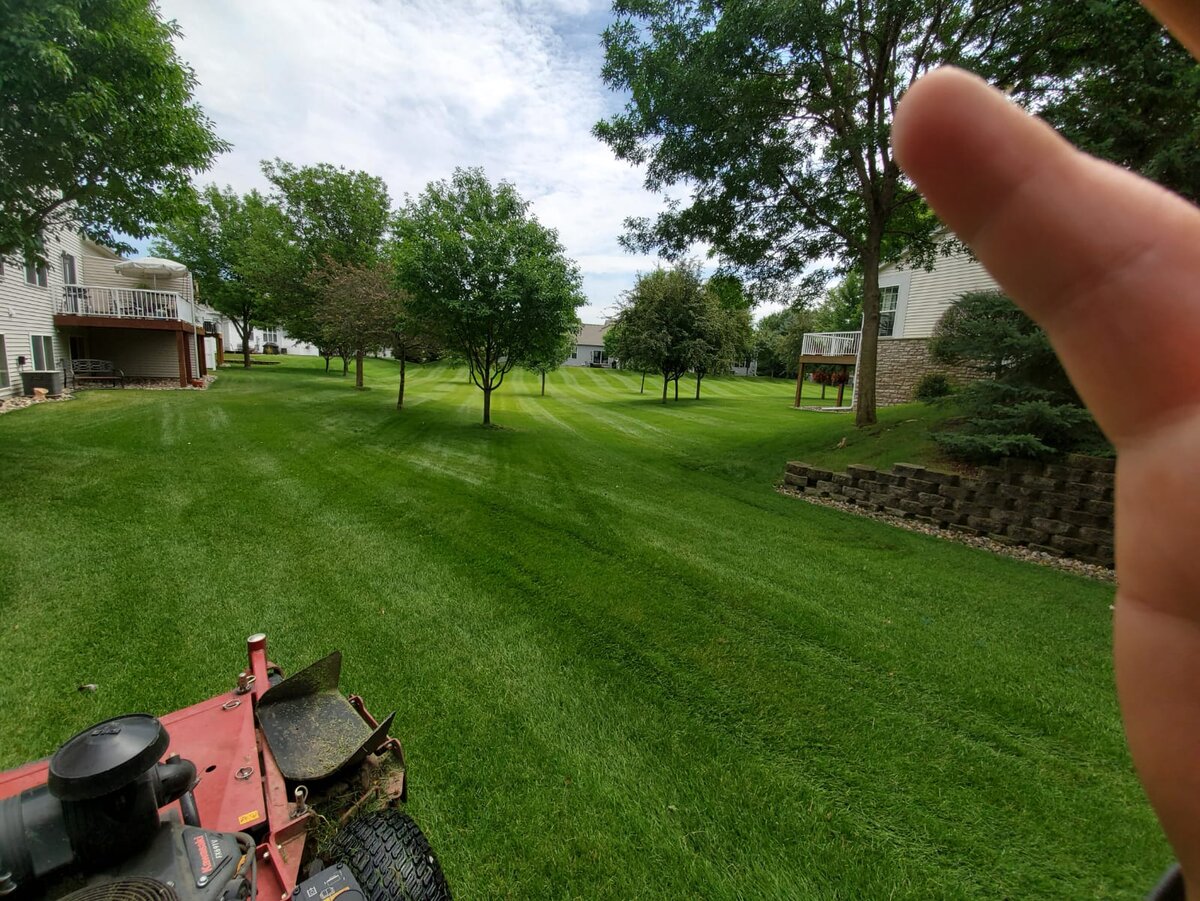 Professional stand-on mower cutting clean lawn striping patterns on a residential property in Clarksville, TN
