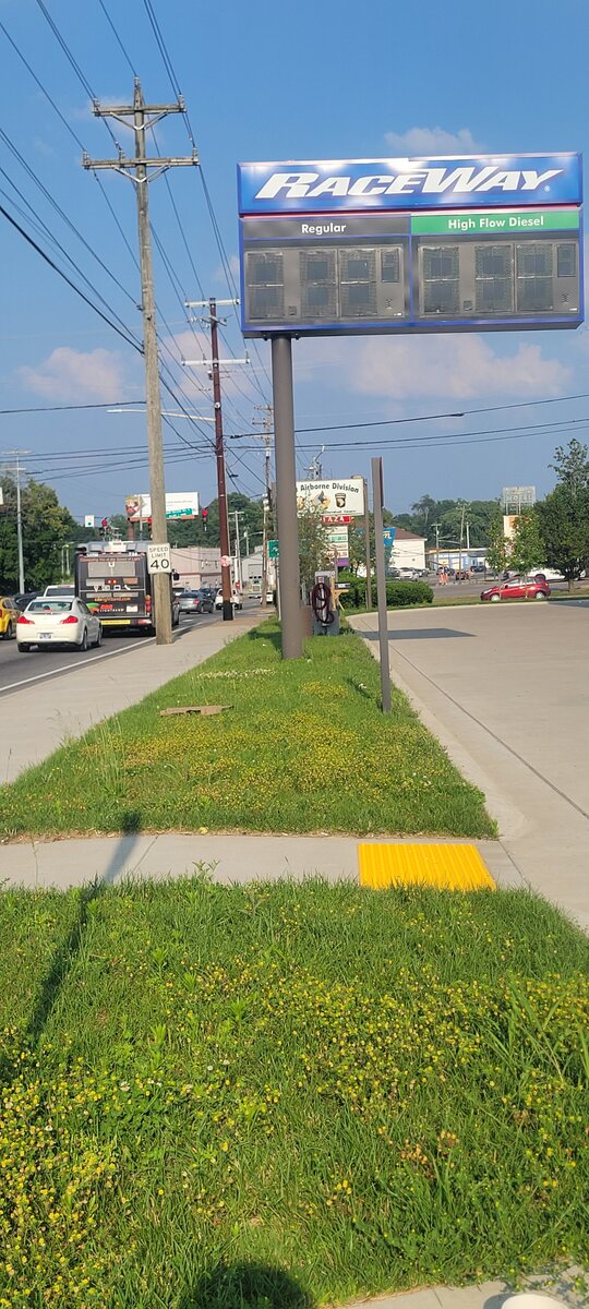 Before commercial lawn cleanup: overgrown grass and weeds along a Raceway gas station sidewalk in Clarksville, TN